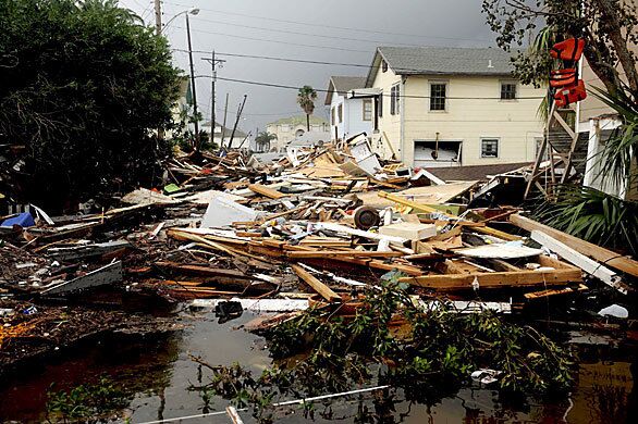 Debris is piled up Sunday between houses in a flooded residential neighborhood of Galveston . The area received additional rain on top of more than 10 inches that accompanied Hurricane Ike.