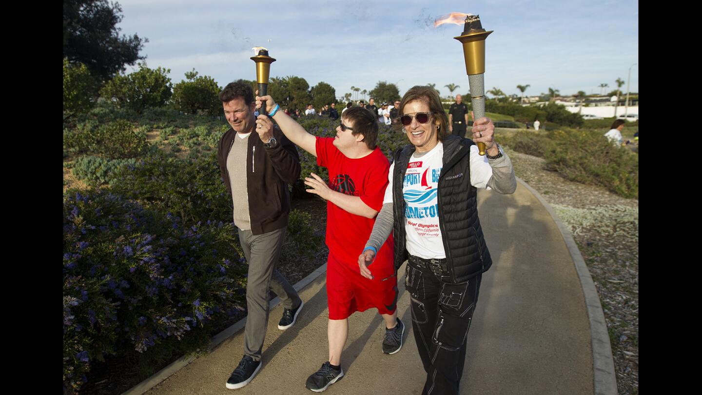 Special Olympics athlete Kevin Woolridge, center, is flanked by volunteer Rodney Weeks and Newport-Mesa Unified School District trustee Karen Yelsey during the Unity Torch Walk at Newport Beach Civic Center on Thursday.