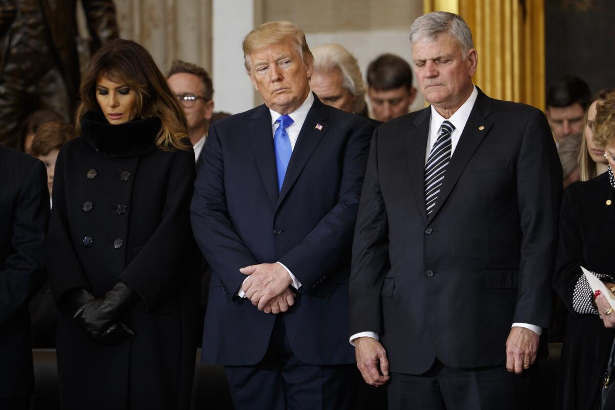 First Lady Melania Trump, President Donald Trump and Franklin Graham pray during a ceremony honoring Rev. Billy Graham in the Rotunda of the U.S. Capitol building in February 2018. Some commentators have said Graham's call for a "special day of prayer" for the president was political in nature.