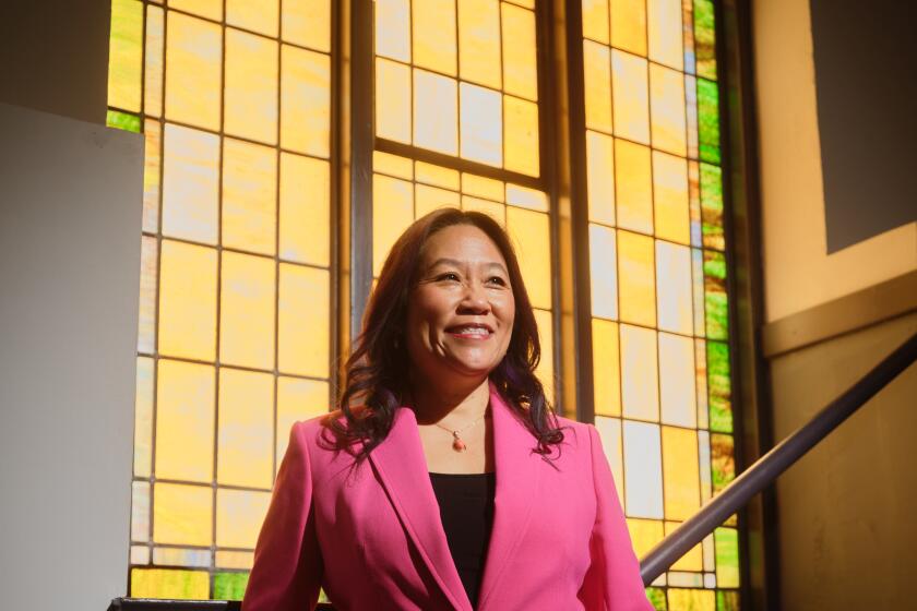 A woman stands in front of a stained glass window.