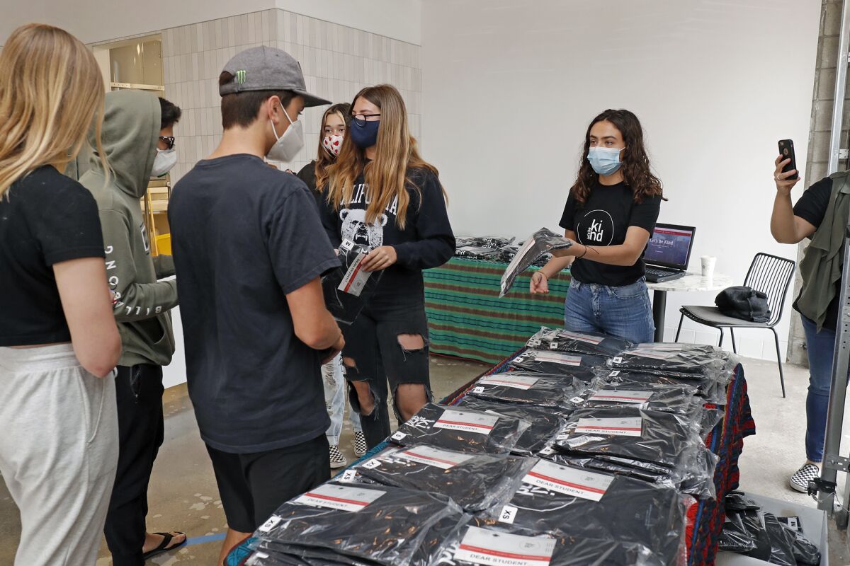 Rebekah Robeck, right, a sophomore at Costa Mesa High School, hands out "Let's Be Kind" T-shirts to a group of eighth-graders from Costa Mesa Middle School at Buenas Coffee on Friday.