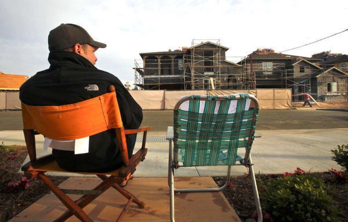 The volume of mortgages to purchase homes is expected to increase next year, but mortgage refinancing will plummet as interest rates rise, the Mortgage Bankers Assn. says. Above, a file photo shows a potential buyer waiting in line in March for a new home in Huntington Beach.