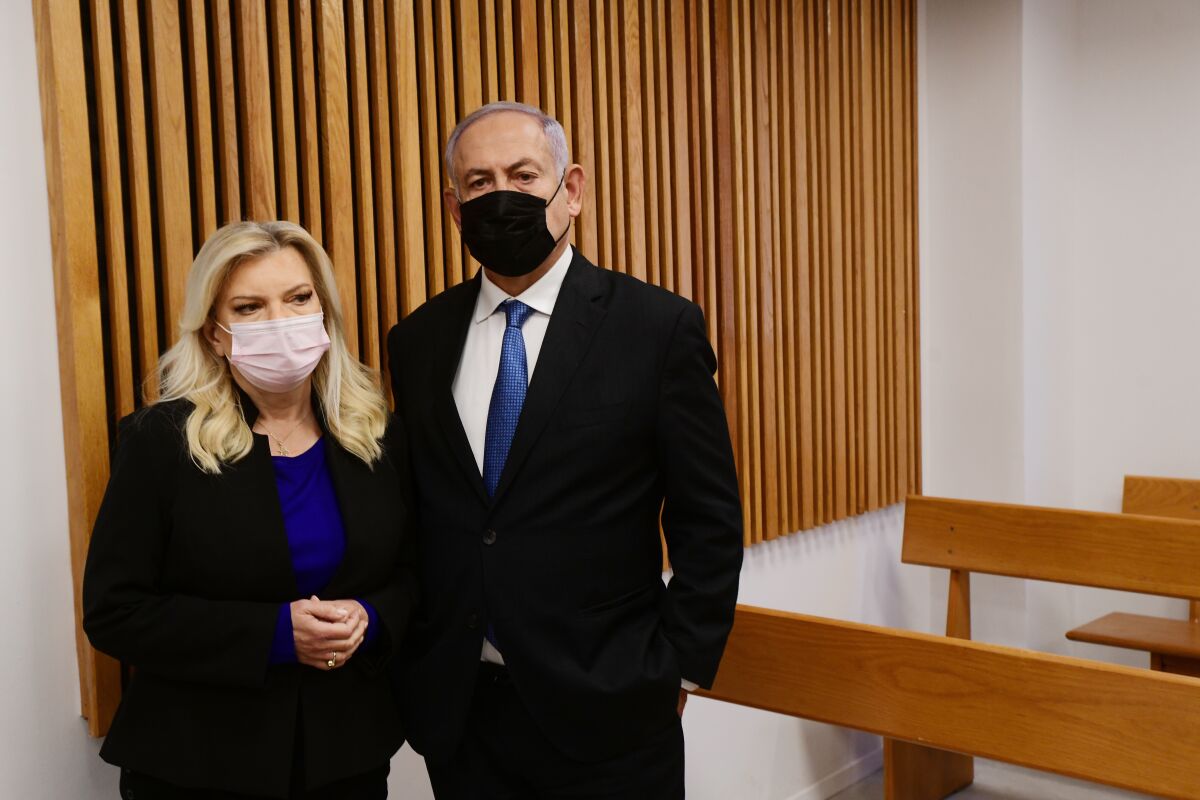 Former Israeli Prime Minister Benjamin Netanyahu and his wife Sarah, stand in the Tel Aviv Magistrate's Court Monday, Jan. 10, 2022, during a preliminary hearing in a defamation lawsuit. Former Prime Minister Benjamin Netanyahu, his wife and son appeared in the Tel Aviv Magistrate’s court Monday for the opening of their case against Olmert, Netanyahu’s predecessor as Israel’s prime minister. The Netanyahus are suing Olmert for saying they suffered from “mental illness” during an interview last year. (Avshalom Sassoni/Pool Photo via AP)