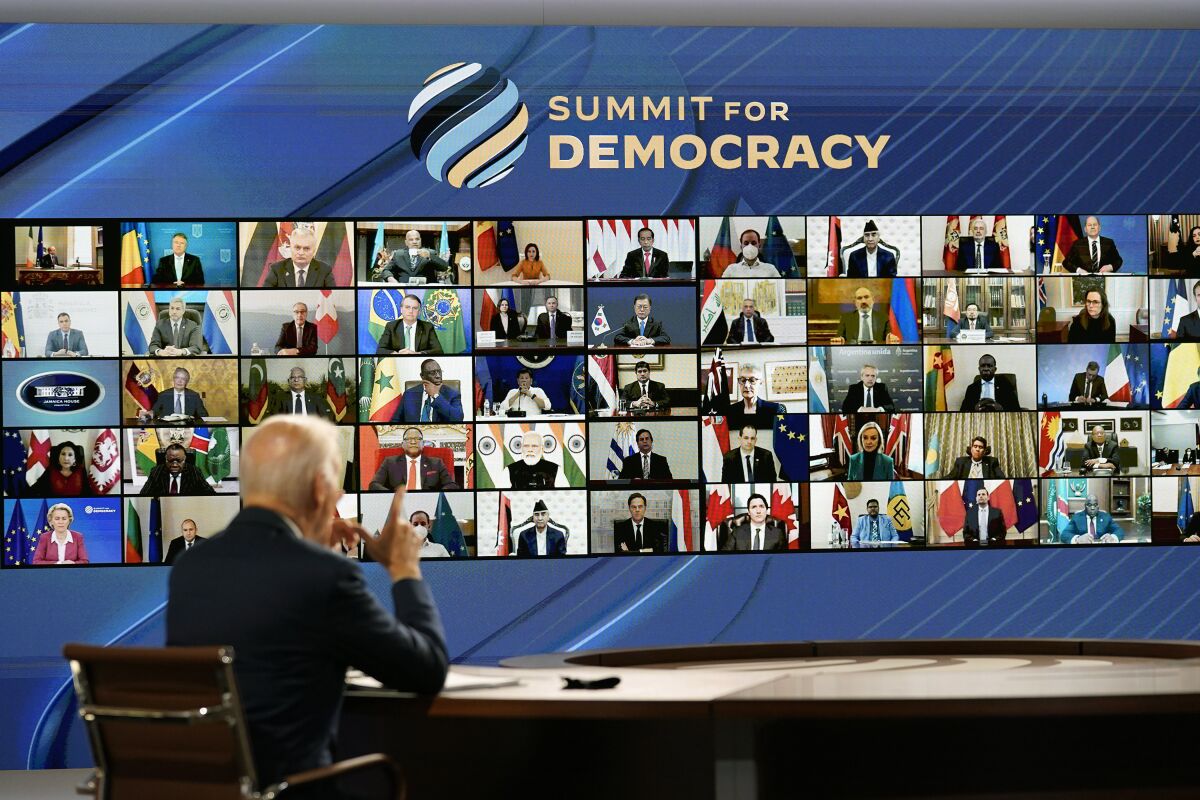 President Biden talks with world leaders on a screen under the banner "Summit for Democracy"