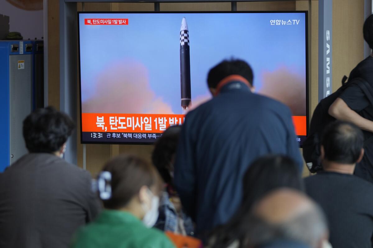 People watch a TV screen showing a missile launch 