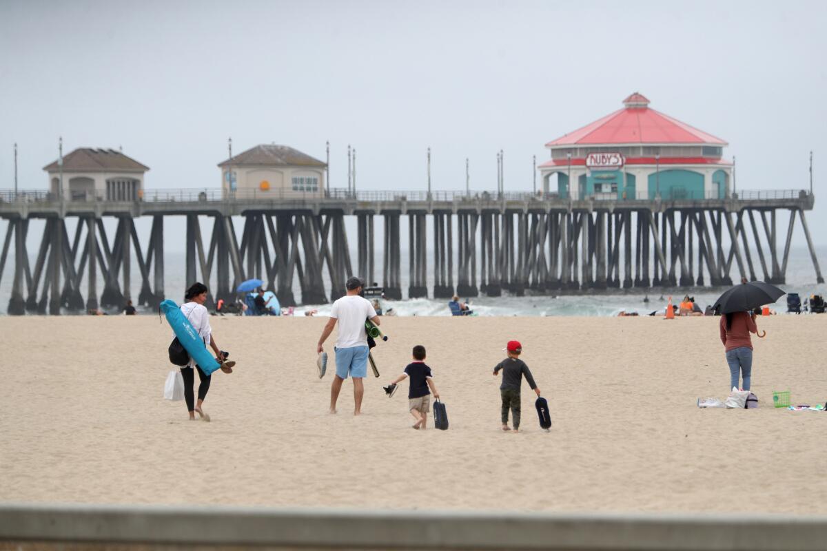 A family arrives for a day at Huntington City Beach in Huntington Beach on Thursday, the same day Gov. Gavin Newsom ordered all state and local beaches in Orange County closed.