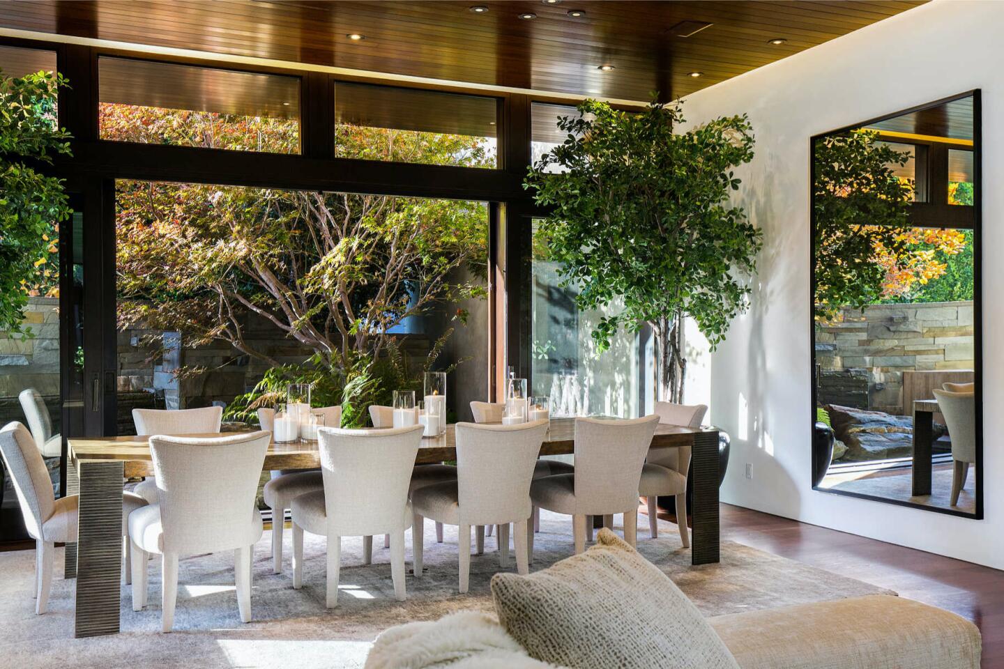 The furnished dining room with big windows overlooking trees.