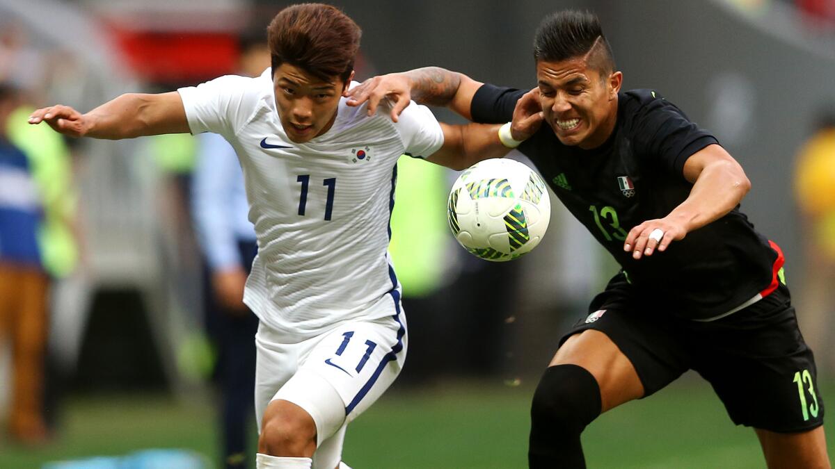 South Korea's Hwang Heechan (11) and Mexico's Salcedo Carlos (13) battle for possession of the ball during a Group C game Wednesday.