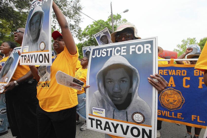 Protesters hold up signs in a march and rally for slain Florida teenager Trayvon Martin in Sanford, Fla., on March 31, 2012.