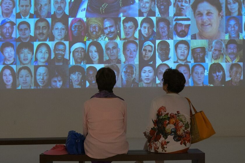Visitors watch the “7 billion Others” video exhibit at the Museum of Photographic Arts in Balboa Park.