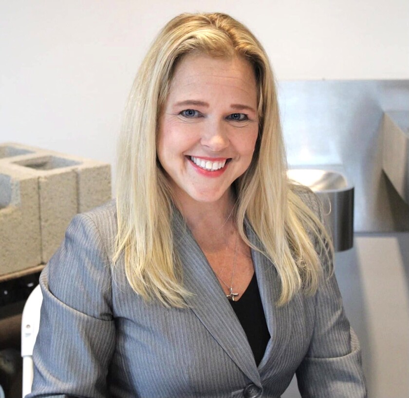 A smiling woman with blond hair and wearing a suit jacket poses for a photo.