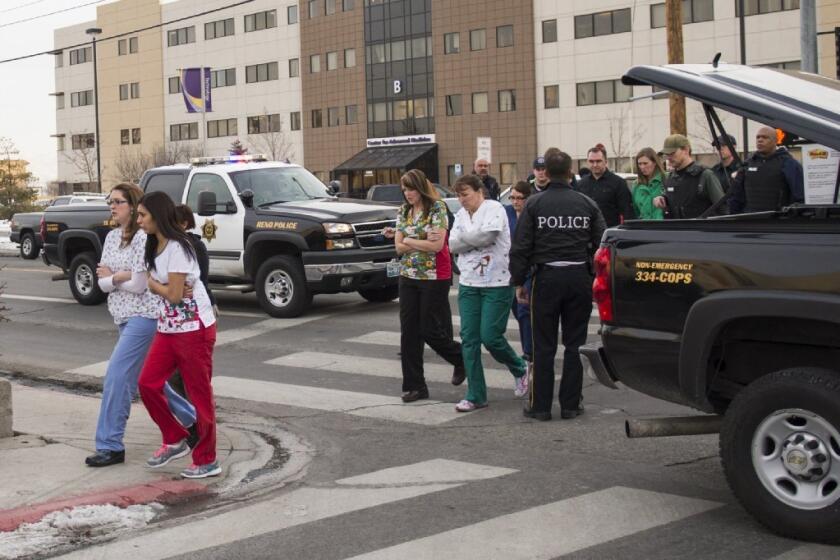 Officers escort witnesses to a bus at the Renown Regional Medical Center after a lone gunman shot and killed a doctor, wounded another doctor and a patient, then took his own life Tuesday in Reno.