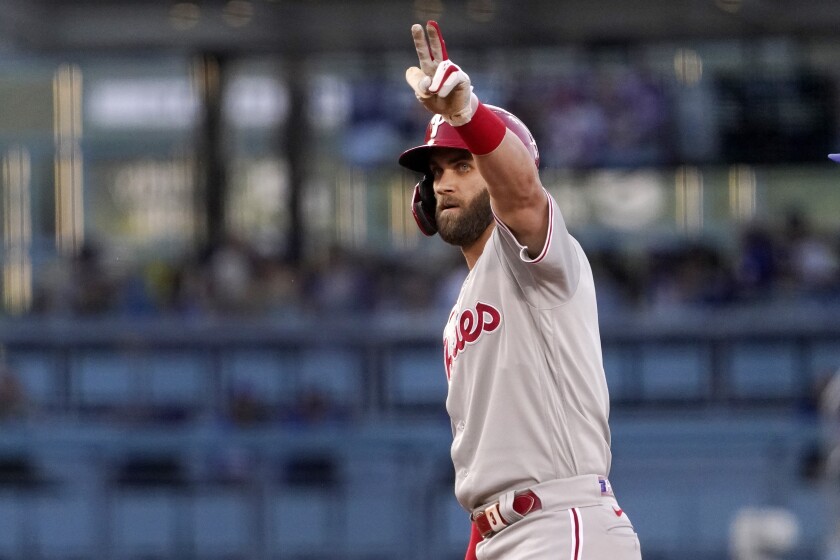 Philadelphia's Bryce Harper gestures to his bench after scoring a double during Saturday's first inning.