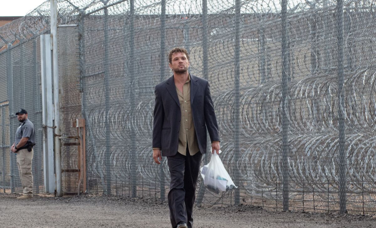 Ryan Phillippe walks along a prison fence in the movie "The Locksmith."