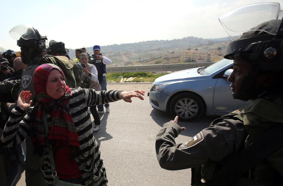A Palestinian woman gestures at an Israeli security officer during clashes at a march against what the Palestinians say is land confiscation by Israel for the building of Jewish settlements, near the West Bank town of Abu Dis on March 17, 2015.