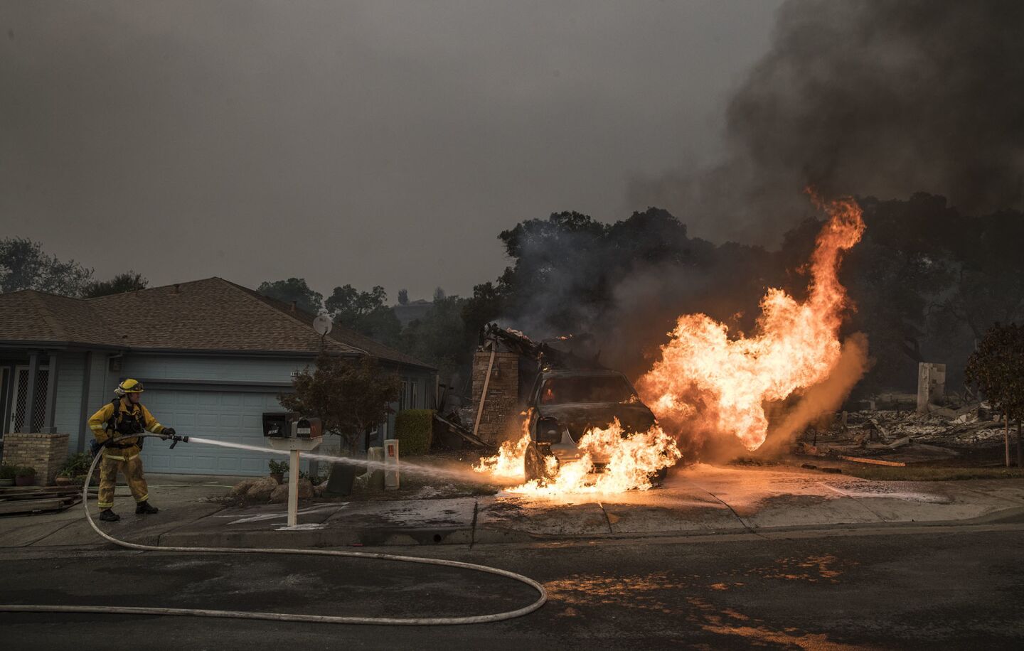 A fcar burns in the driveway of a destroyed home in Fountaingrove Village.