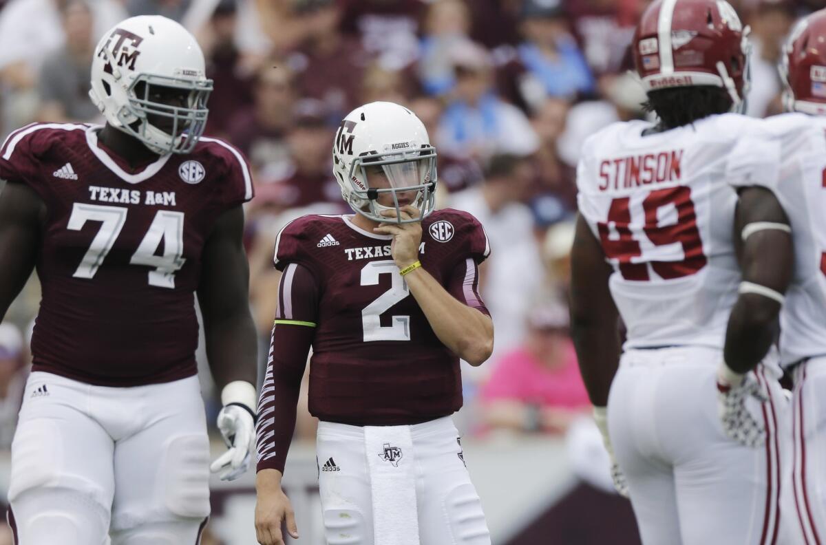 Texas A&M; quarterback Johnny Manziel stands head and shoulders below Aggies offensive lineman Germain Ifedi and Alabama defensive lineman Ed Stinson.