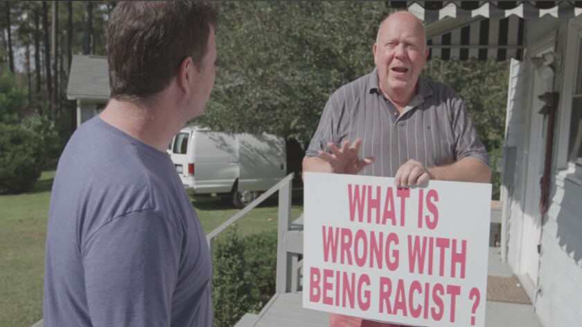 Filmmaker Andrew Goldberg with Russell Walker, who holds a sign that reads 'What is wrong with being racist?' in the documentary 'Viral: Antisemitism in Four Mutations'