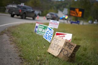 FILE - A makeshift cardboard sign leans up against campaign posters near a relief center on Oct. 3, 2024, in Vilas, N.C. in the aftermath of hurricane Helene. (AP Photo/Chris Carlson, file)