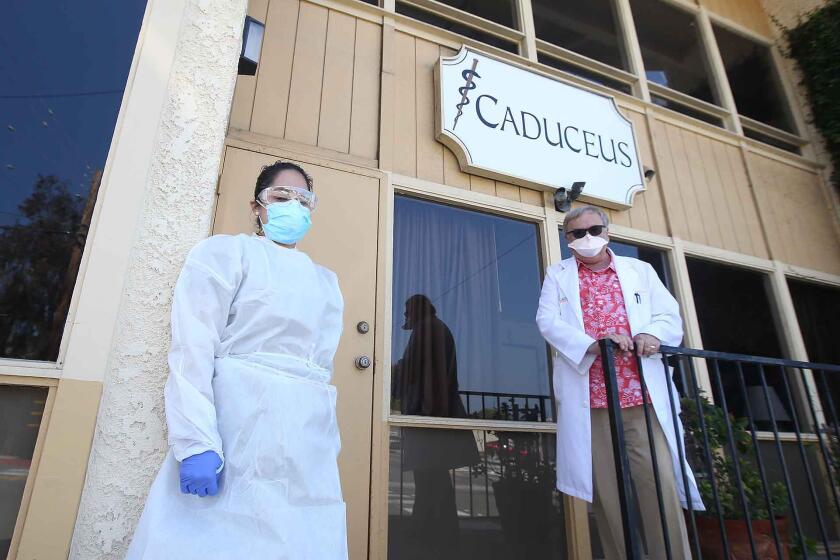 Assistant Janet Muratalla, left, and Dr. Gregg DeNicola wait to administer curbside coronavirus testing at the Caduceus Medical Group in Laguna Beach.