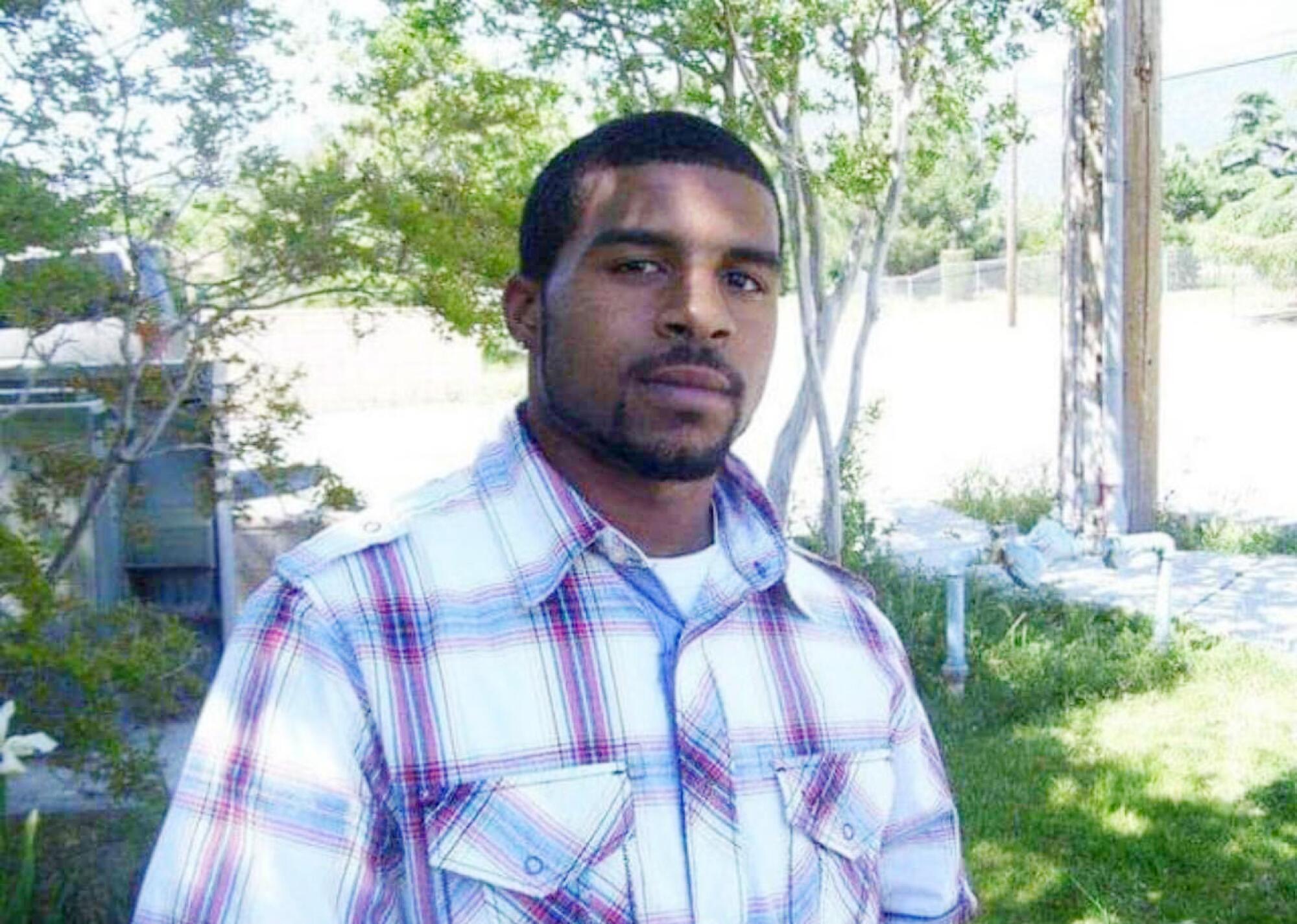 A man in a collared shirt stands in a yard