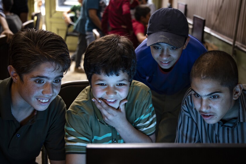 Four boys crowd around a computer monitor