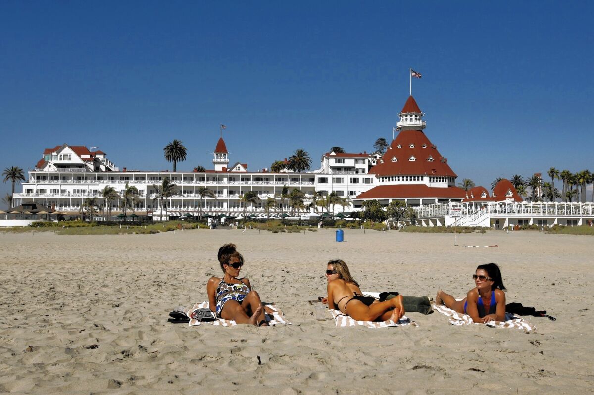 Beachgoers relax on the sand near the historic Hotel del Coronado in San Diego.