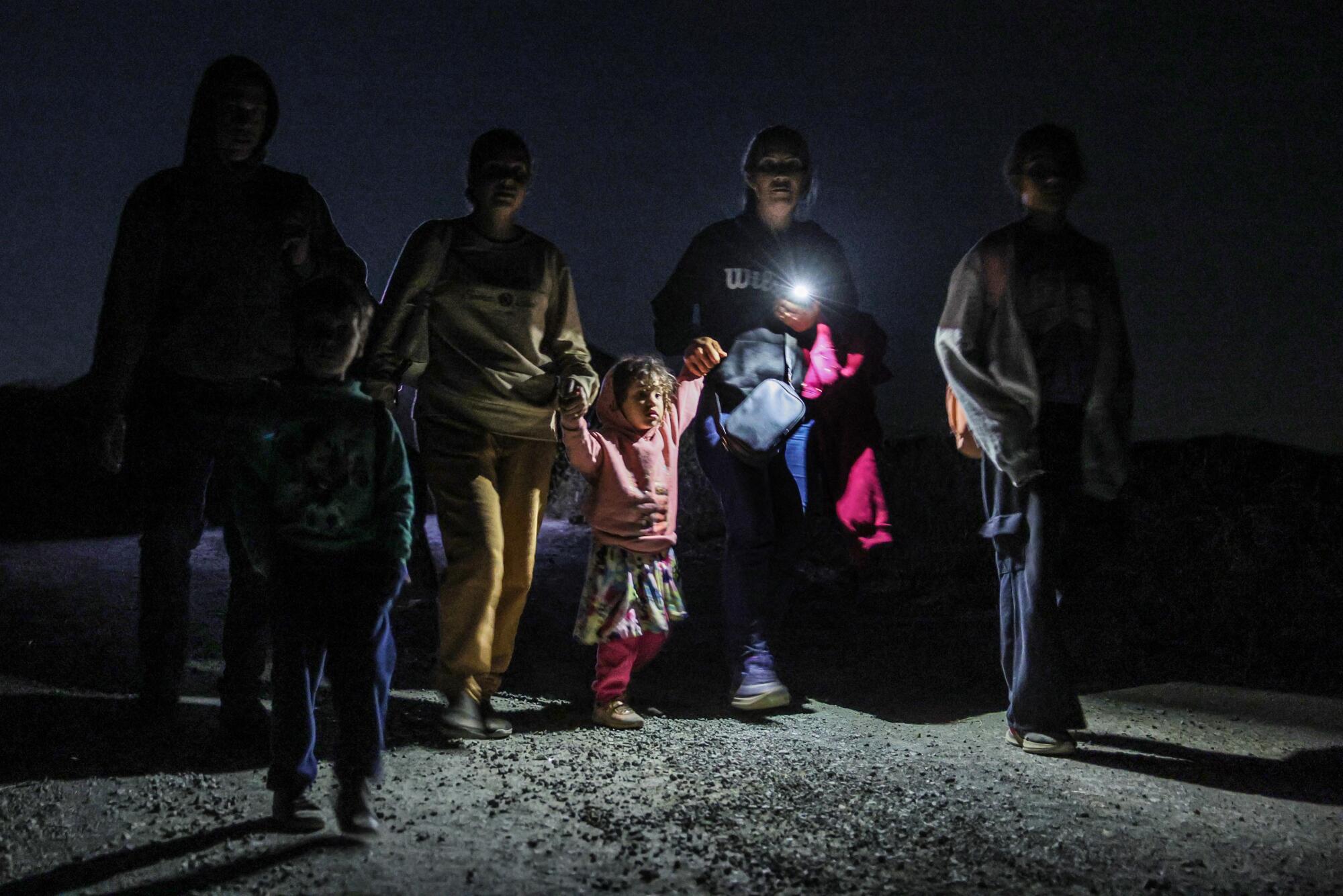 一个疲惫不堪的家庭在穿越美墨边境后结束了 9 个多小时的徒步旅行。