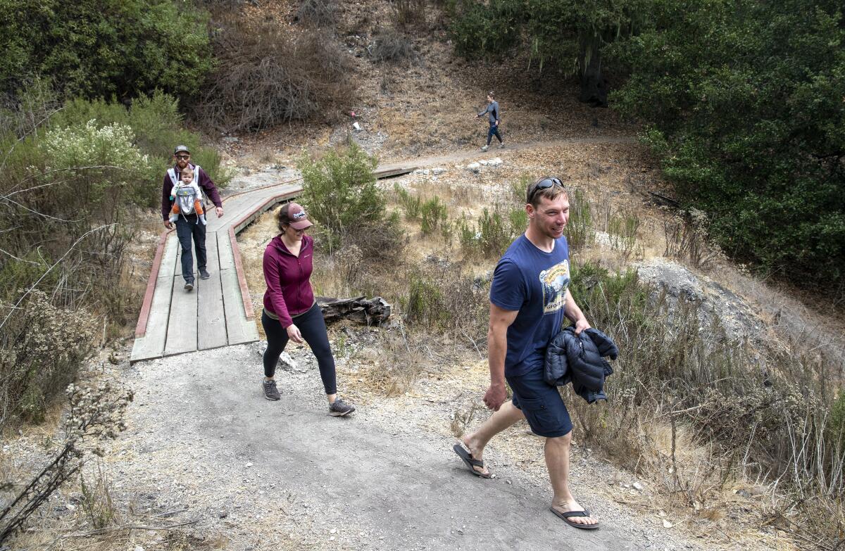 Hikers cross a dry creek along the Spring to Spring Trail at the Pismo Preserve.