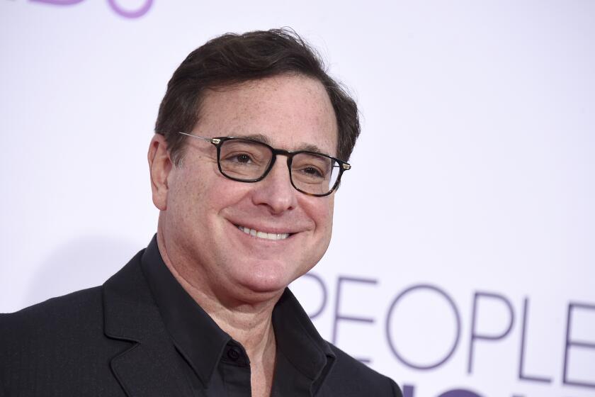 A man wearing black smiles as he arrives at an awards show