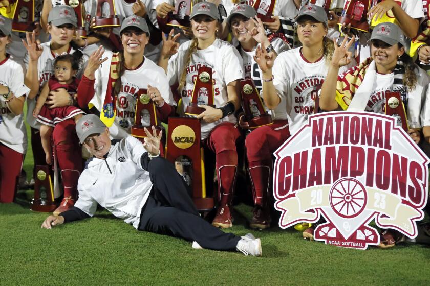 FIKE - Oklahoma coach Patty Gasso, front left, and players pose for a photo while holding up three fingers after defeating Florida State in the NCAA Women's College World Series championship series Thursday, June 8, 2023, in Oklahoma City. Oklahoma begins its quest for an unprecedented fourth consecutive national softball title. (AP Photo/Nate Billings, File)