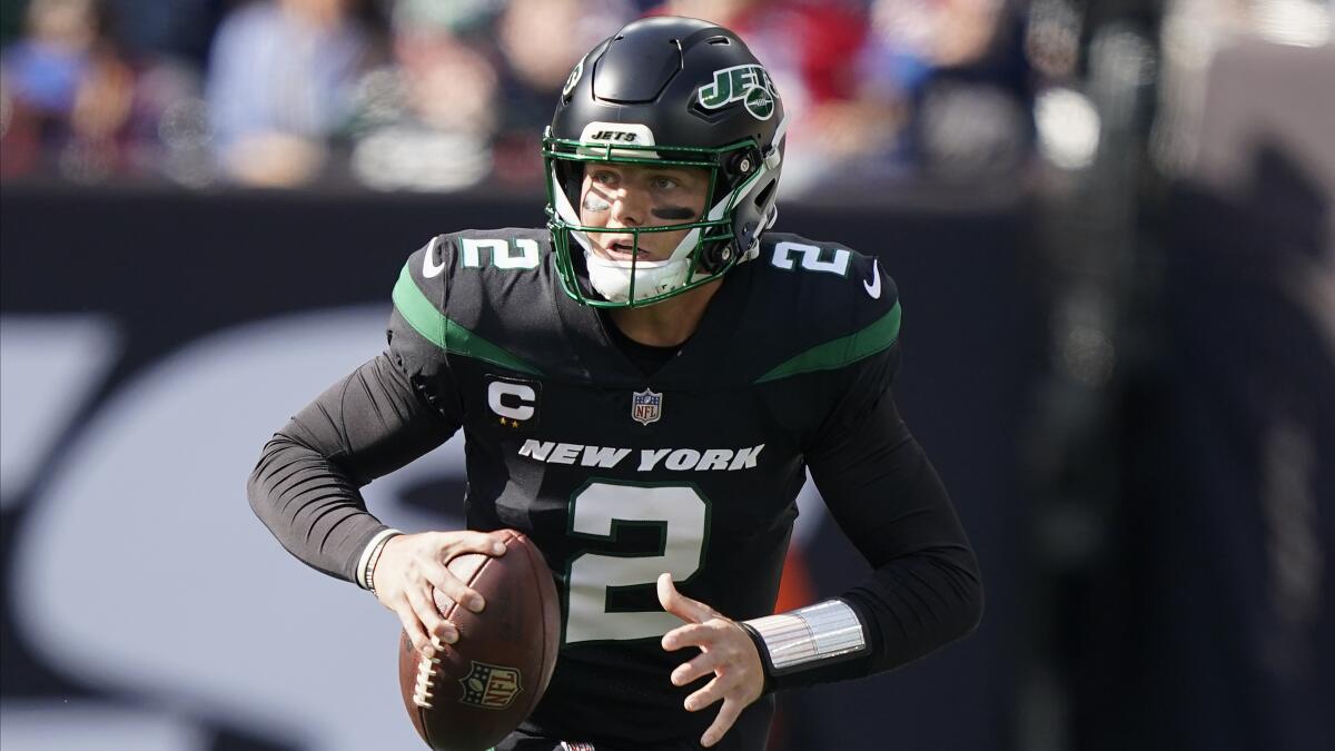 New York Jets quarterback Zach Wilson rolls out of the pocket to pass against the New England Patriots.