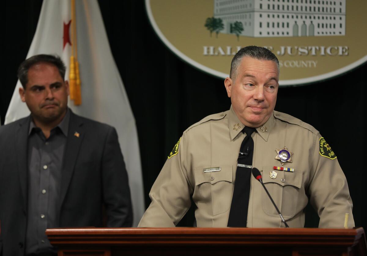 Los Angeles County Sheriff Alex Villanueva stands at a lectern in front of the Hall of Justice sign