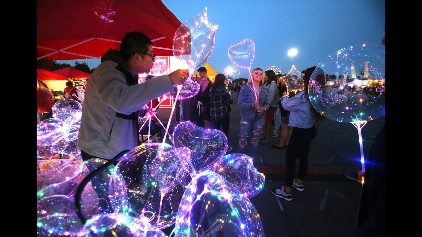 Johnny Lin hands out "bubble balloons" at dusk Friday during the OC Night Market at the OC Fair & Event Center in Costa Mesa. The market continues through Sunday.