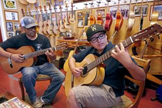 Candelas Guitars owner Tomas Delgado, left, keeps an eye on student Eloy González