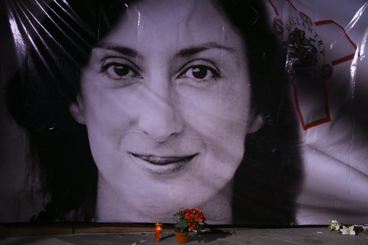 FILE - In this Tuesday, Oct. 16, 2018 file photo, flowers and a candle lie in front of a portrait of slain investigative journalist Daphne Caruana Galizia during a vigil outside the law courts in Valletta, Malta. After a long process of compiling evidence and witness testimony, indictment on charges of complicity in the murder and for criminal conspiracy was filed against Yorgen Fenech, a hotelier whom investigators believe masterminded the killing. (AP Photo/Jonathan Borg, File)