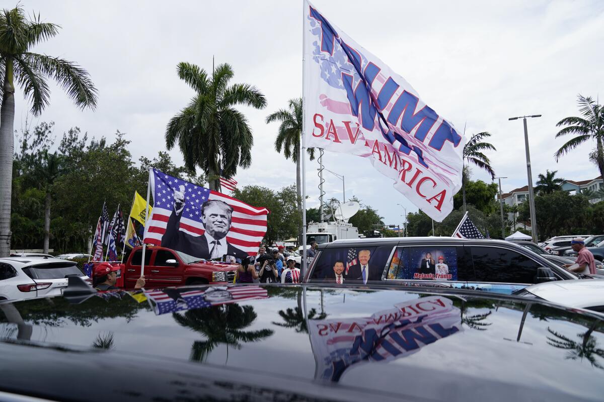 Supporters of former President Trump wave flags bearing his name and image