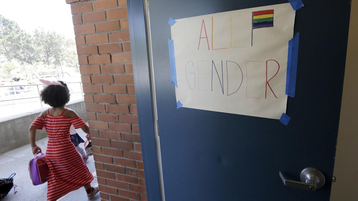 A camper walks past a sign for an all-gender bathroom at the Bay Area Rainbow Day Camp in El Cerrito on July 11, 2017.