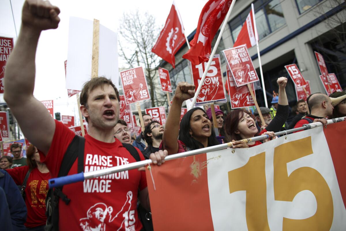 Organizer Bryan Watson, left, gestures during a march to raise the minimum wage to $15 per hour in Seattle.