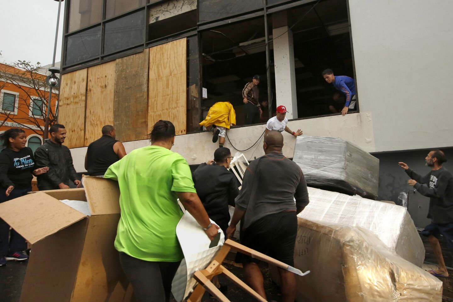 People loot a furniture store in a section of Old San Juan after Maria damaged buildings.
