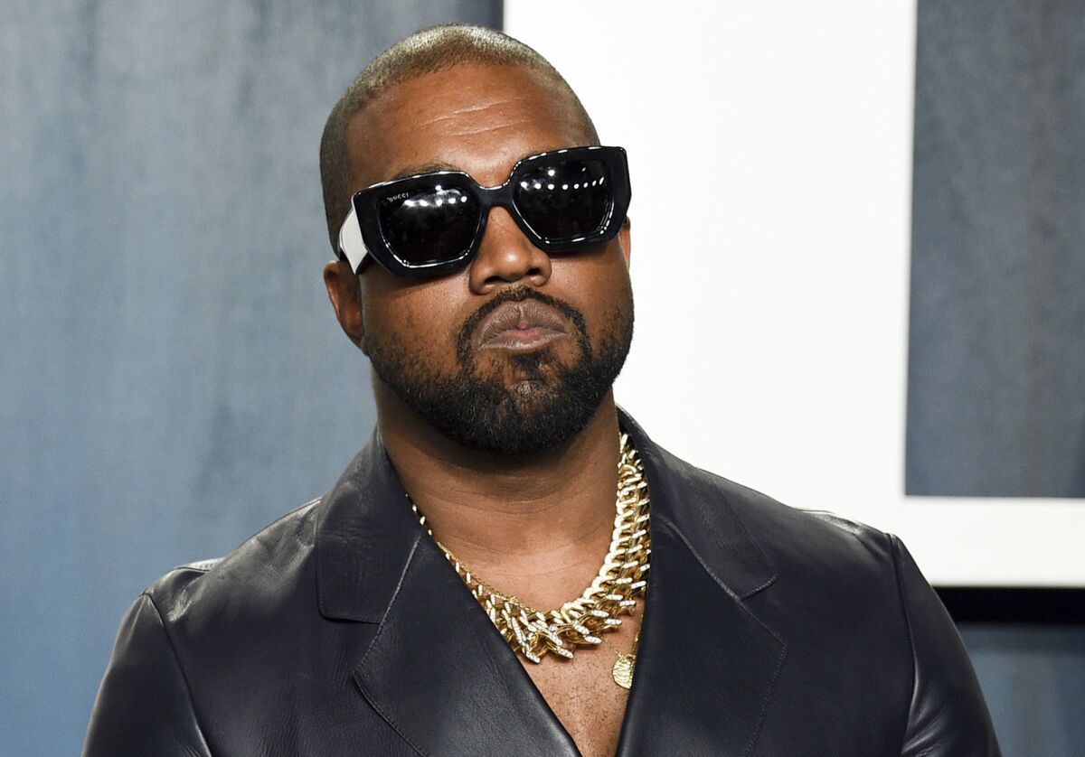 Kanye West wearing sunglasses and a gold chain around his neck.