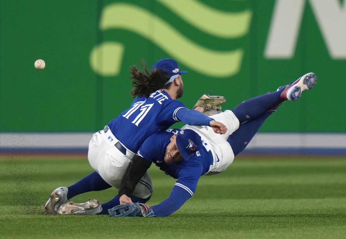 Toronto Blue Jays shortstop Bo Bichette (11) and center fielder George Springer (4) collide while to trying to catch a three-RBI double off the bat of Seattle Mariners shortstop J.P. Crawford during the eighth inning of Game 2 of a baseball AL wild-card playoff series, Saturday, Oct. 8, 2022, in Toronto. (Frank Gunn/The Canadian Press via AP)