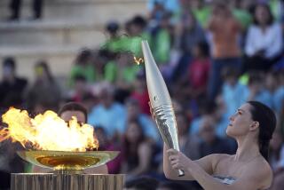 La actriz Mary Mina, como una sacerdotisa griega, sostiene una antorcha con la llama de los Juegos Olímpicos, en el Estadio Panatenaico de Atenas, donde se celebraron los primeros Juegos Olímpicos de la actual era, en 1896. (AP Foto/Petros Giannakouris)