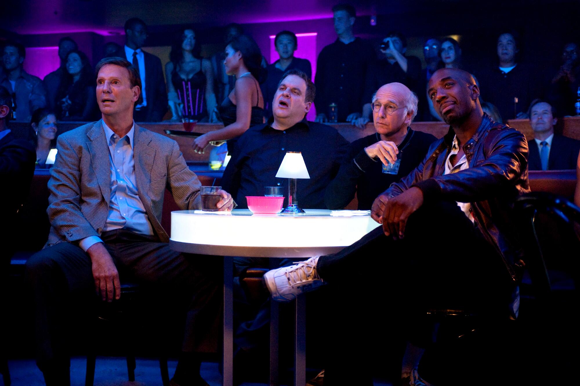 Four men around a nightclub table