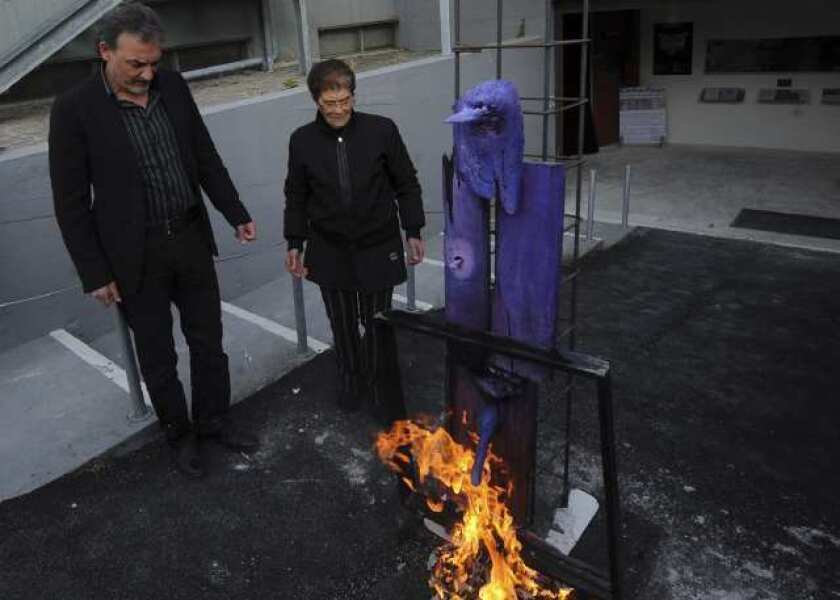 Antonio Manfredi, director of the Casoria Contemporary Art Museum, and Italian artist Rosaria Matarese burn one of Matarese's creations in front of the museum on Wednesday.