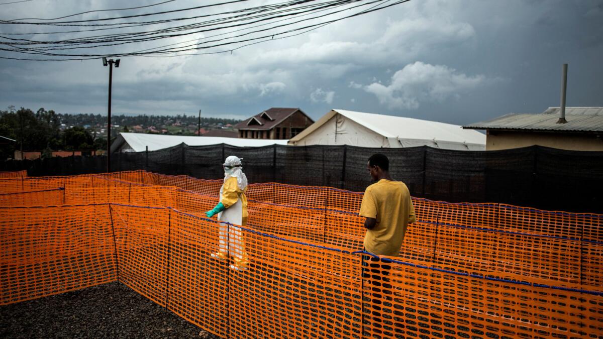 A health worker escorts an unconfirmed Ebola patient to his room this month at a Doctors Without Borders treatment center in Bunia, Congo.