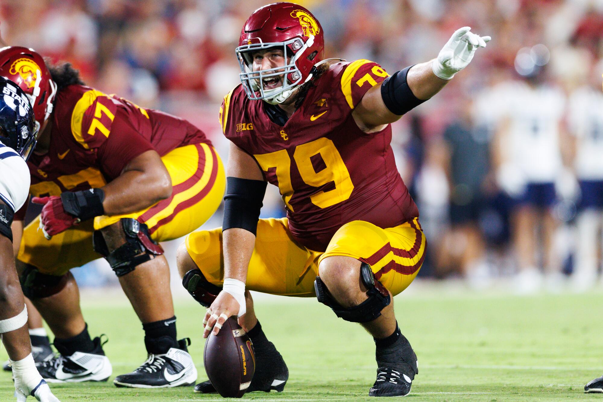 UCLA center Jonah Monheim points and shouts while kneeling over the ball