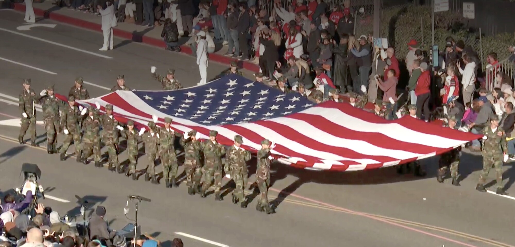 افرادی با لباس نظامی پرچم بزرگ ایالات متحده را حمل می کنند.
