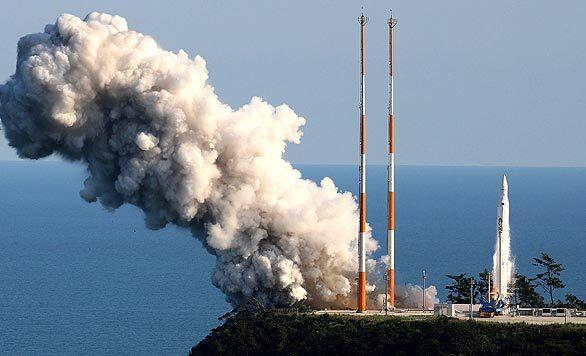 A rocket carrying South Korea's first home-launched satellite rises from the launch pad, right, at Naro space center. The launch of the scientific satellite had been postponed twice by technical problems. Seoul says the mission is part of a peaceful civilian space program, rejecting any comparison with North Korea's missile launch earlier this year.