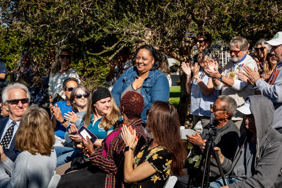 A woman stands up in a crowd as people clap